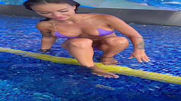 Monika fox in purple bikini swims in pool & poses by window against background of city free