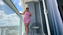 Hot MILF strips out of her pink dress and plays with her pussy on balcony