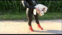 Fetish masked slave dressed in latex wandering in the countryside