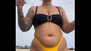 Usando um biquini amarelo bem apertado rachando a buceta pra chamar atenção na praia