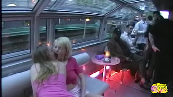 Two women engaged in a provocative display of affection and intimate interaction aboard a vessel situated in the city of paris