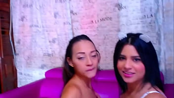 Intense kisses between two friends touching each other's pussies on the sofa