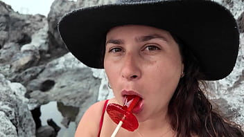 A stepmom practices sucking on a candy on the beach then tests her skills on her stepson's dick