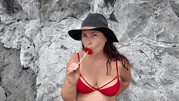 A stepmom practices sucking on a candy on the beach then tests her skills on her stepson's dick