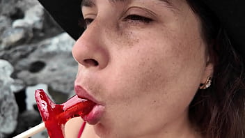 A stepmom practices sucking on a candy on the beach then tests her skills on her stepson's dick