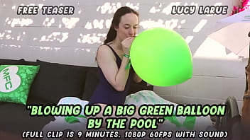 Blowing up a big green balloon by the pool