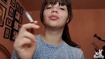 Brunette with natural big lips with natural color lipgloss smoking a cigarette blowing smoke in your face