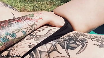 Tattooed horny brunette with big boobs sunbathing in the yard and rubbing sunscreen on her tits
