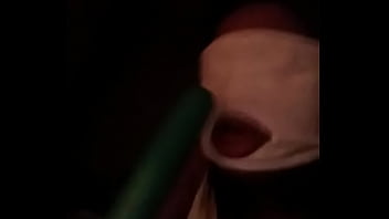 Sucking on a green dildo with mouth mask