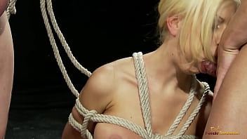 A sexy blonde babe in red stockings receives discipline from two horny guys by sucking off their hard cocks before she gets tied up with rope so they can fuck her tight cunt and cum on her face