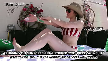 Rubbing on sunscreen in a striped two piece swimsuit