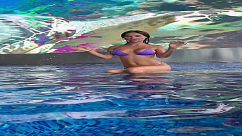Monika fox in purple bikini swims in pool & poses by window against background of city free