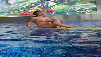 Monika fox in purple bikini swims in pool & poses by window against background of city free Monika fox in purple bikini swims in pool & poses by window against background of city free