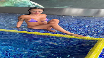Monika fox in purple bikini swims in pool & poses by window against background of city free