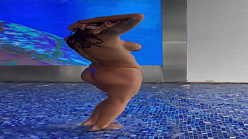 Monika fox in purple bikini swims in pool & poses by window against background of city free