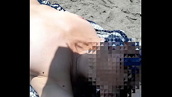 Arama desnuda en la playa luciendo sus marquitas