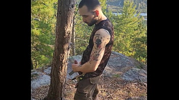 Bearded tattooed hunk blowing a load on the mountain