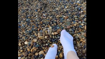 Playing with my feet in white socks with pebbles on the beach