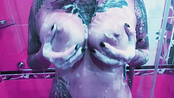 Curvy girl washes her huge tits with soap and rubs them on the glass