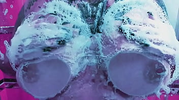Curvy girl washes her huge tits with soap and rubs them on the glass