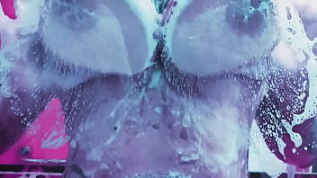 Curvy girl washes her huge tits with soap and rubs them on the glass