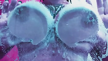 Curvy girl washes her huge tits with soap and rubs them on the glass