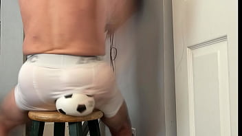 Groin stretch in tight spandex shorts with mini football soccer ball on stool and table slowed down time lapse