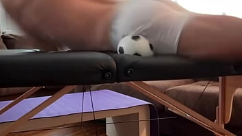 Groin stretch in tight spandex shorts with mini football soccer ball on stool and table slowed down time lapse