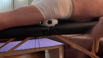 Groin stretch in tight spandex shorts with mini football soccer ball on stool and table slowed down time lapse