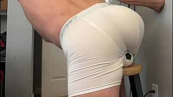 Groin stretch in tight spandex shorts with mini football soccer ball on stool and table slowed down time lapse