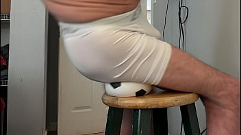 Groin stretch in tight spandex shorts with mini football soccer ball on stool and table slowed down time lapse